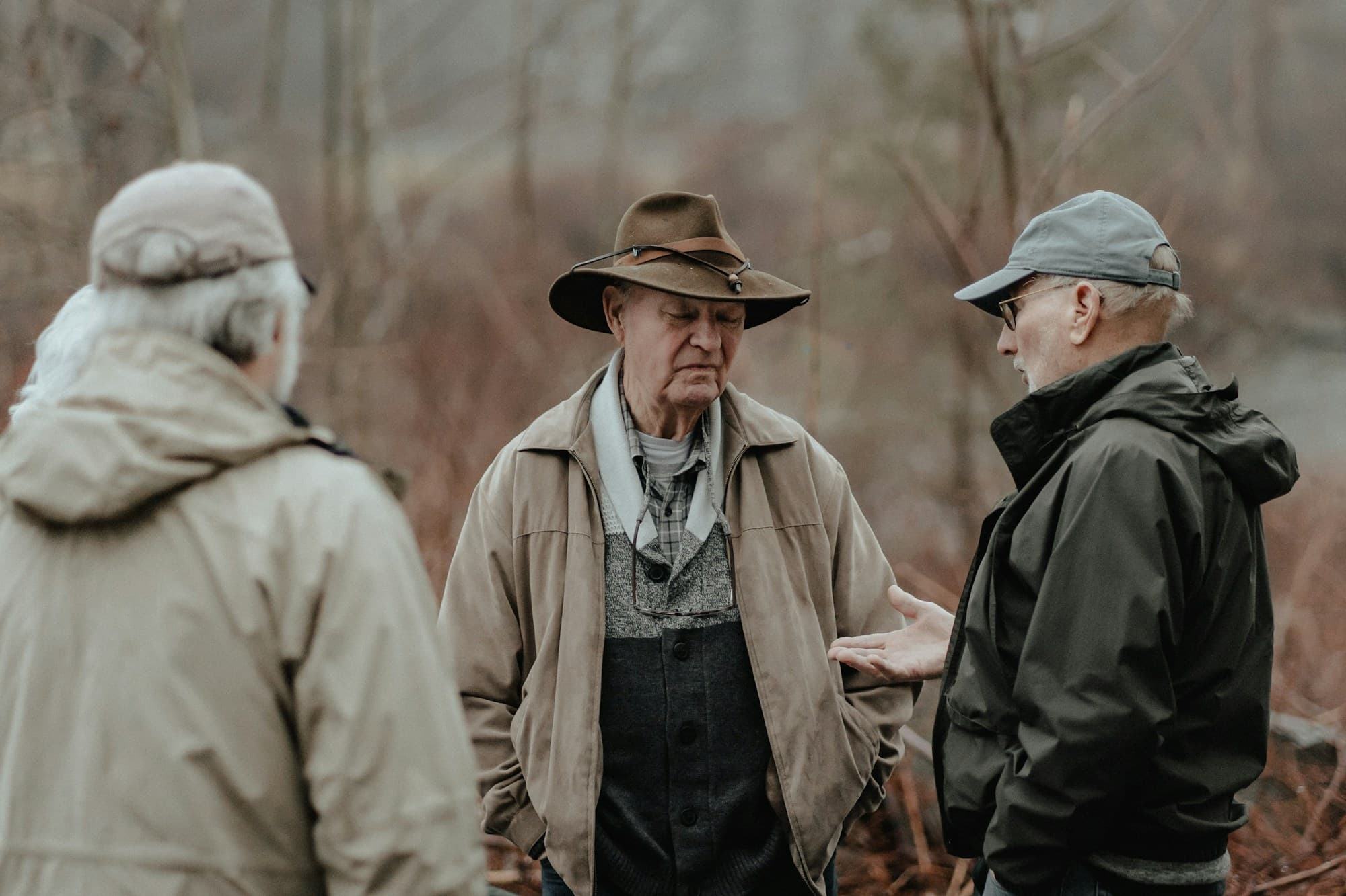 Três homens conversando ao ar livre em área rural