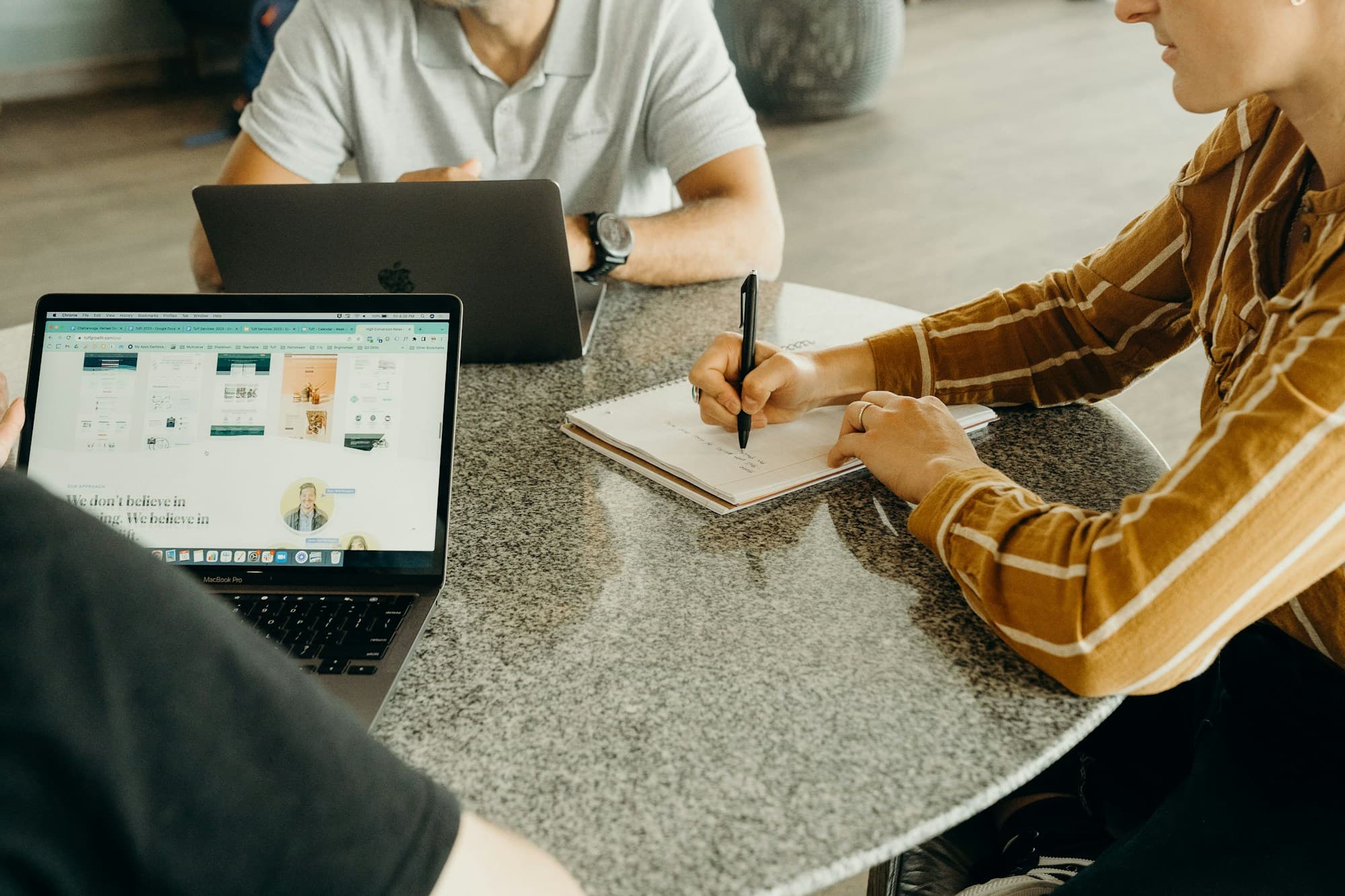 Reunião de trabalho em mesa com laptops e caderno de anotações